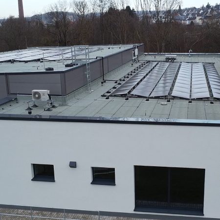 Energetische Sanierung Schwimmbad Gebäudeansicht mit Schwimmbecken und PVT-Flachdachanlage Copyright Giersch